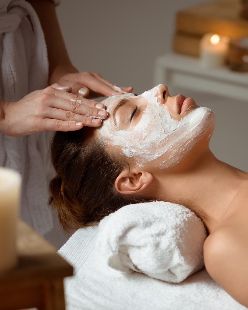 jeune-femme-au-masque-pour-le-visage-relaxant-dans-le-salon-spa -verticale