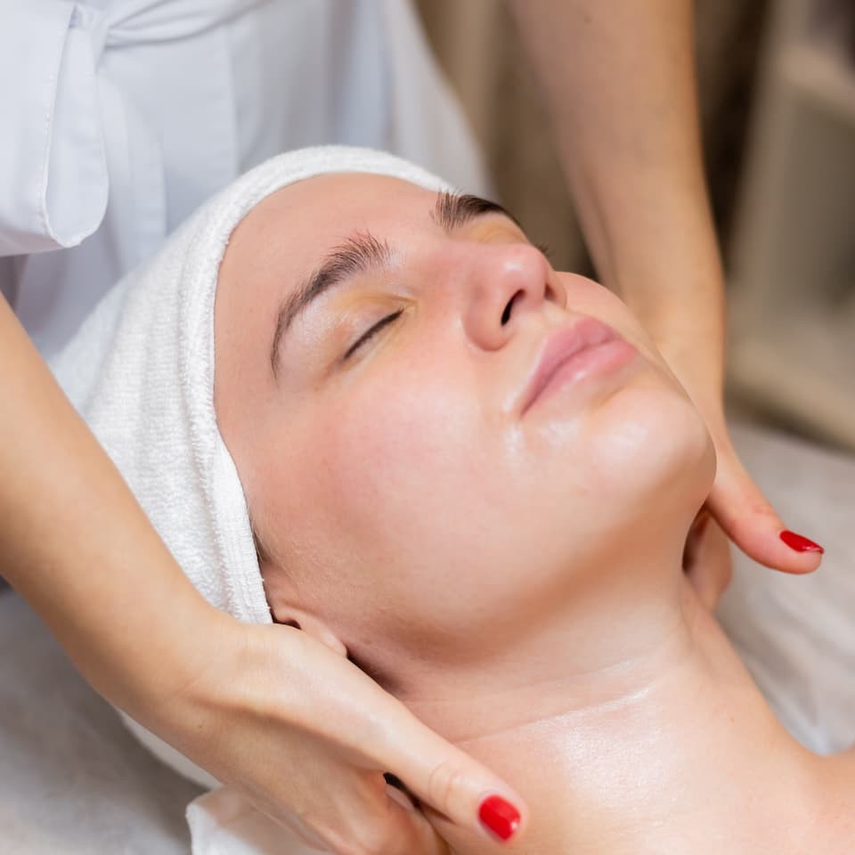 une-belle-jeune-fille-est-allongee-sur-la-table-de-l-estheticienne-et-recoit-des-procedures-un-leger-massage-du-visage-a-l-huile (1)